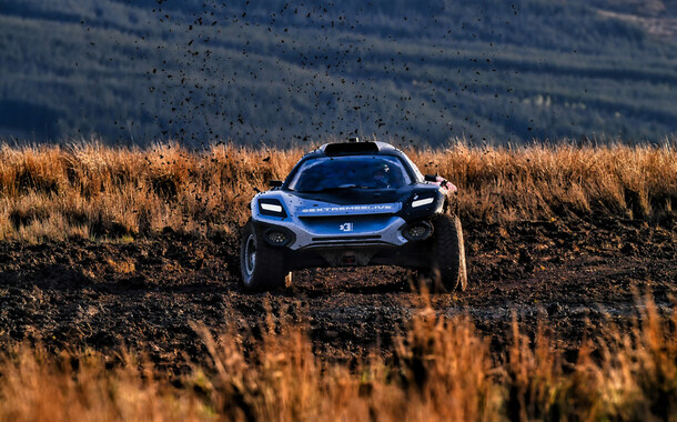 Rallyauto fährt in einer kargen Landschaft.